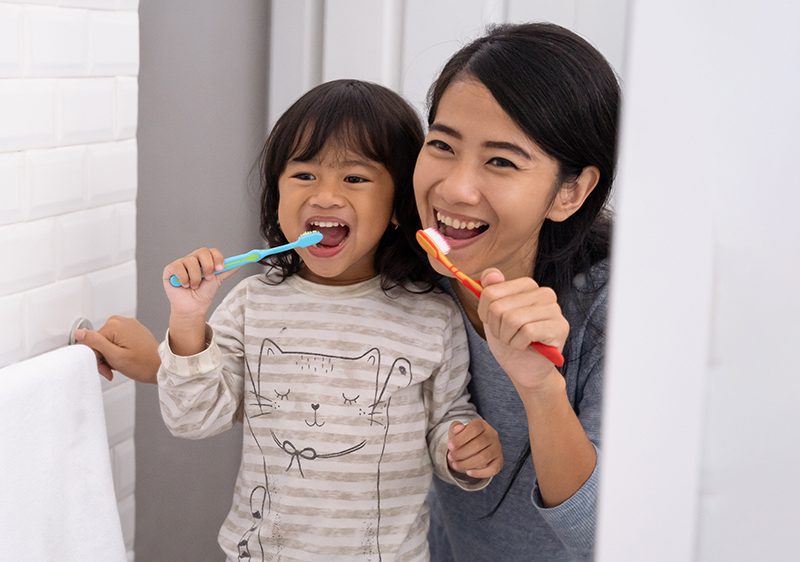 mother daughter brushing teeth